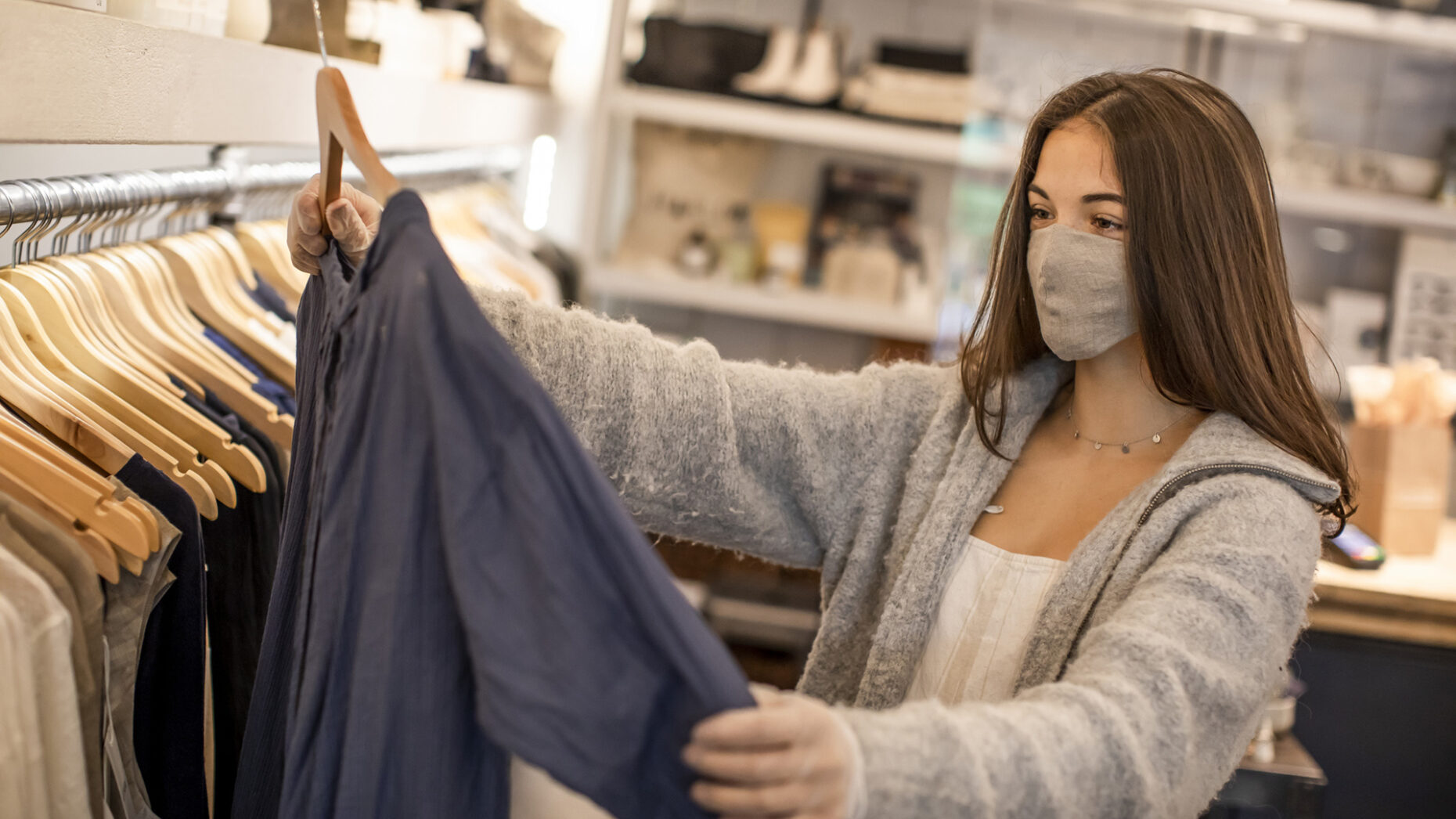 Young teenager shopping for clothing wearing protective gloves.